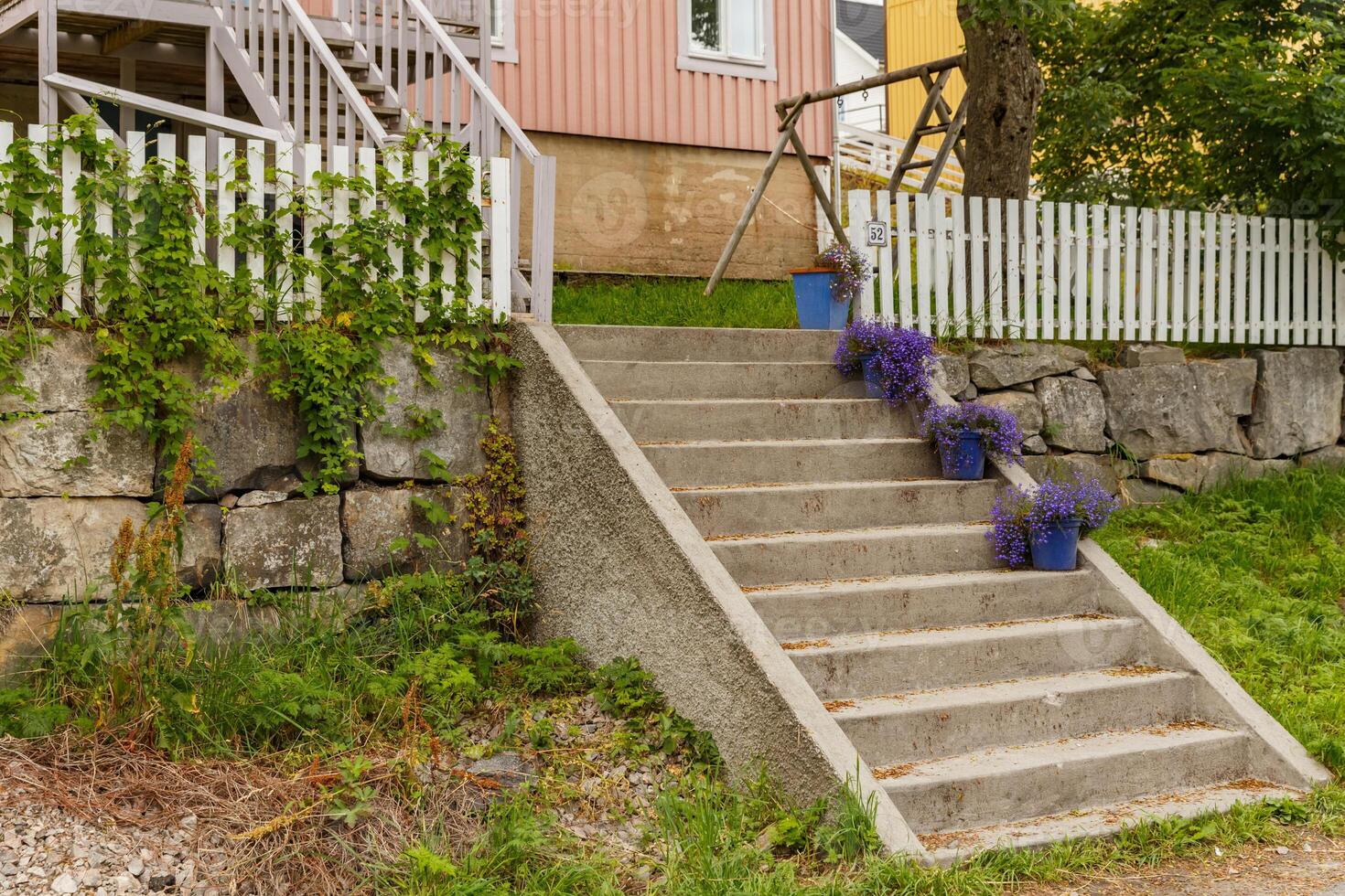 Porch of the house with steps, the facade of the house, violet flowers, the white windows of the house, rural scene photo