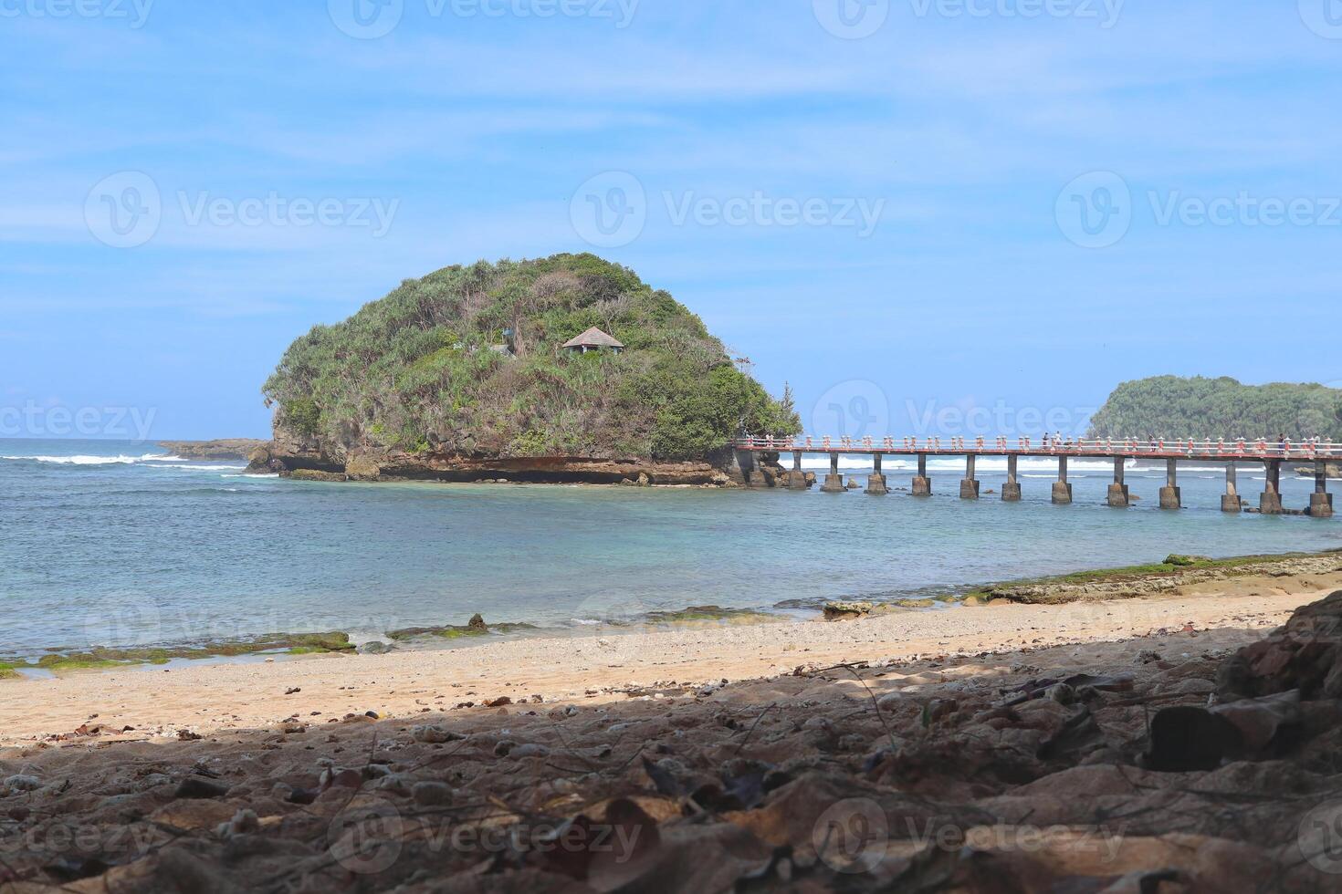 Balekambang Beach on a sunny day with bright blue skies and Ismoyo Island visible in the distance photo
