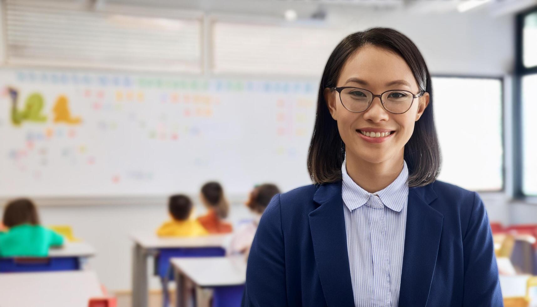 Japanese preschool teacher smiling warmly in a classroom filled with children. The teacher, The vibrant learning environment in the background makes this image perfect for educational themes, school photo