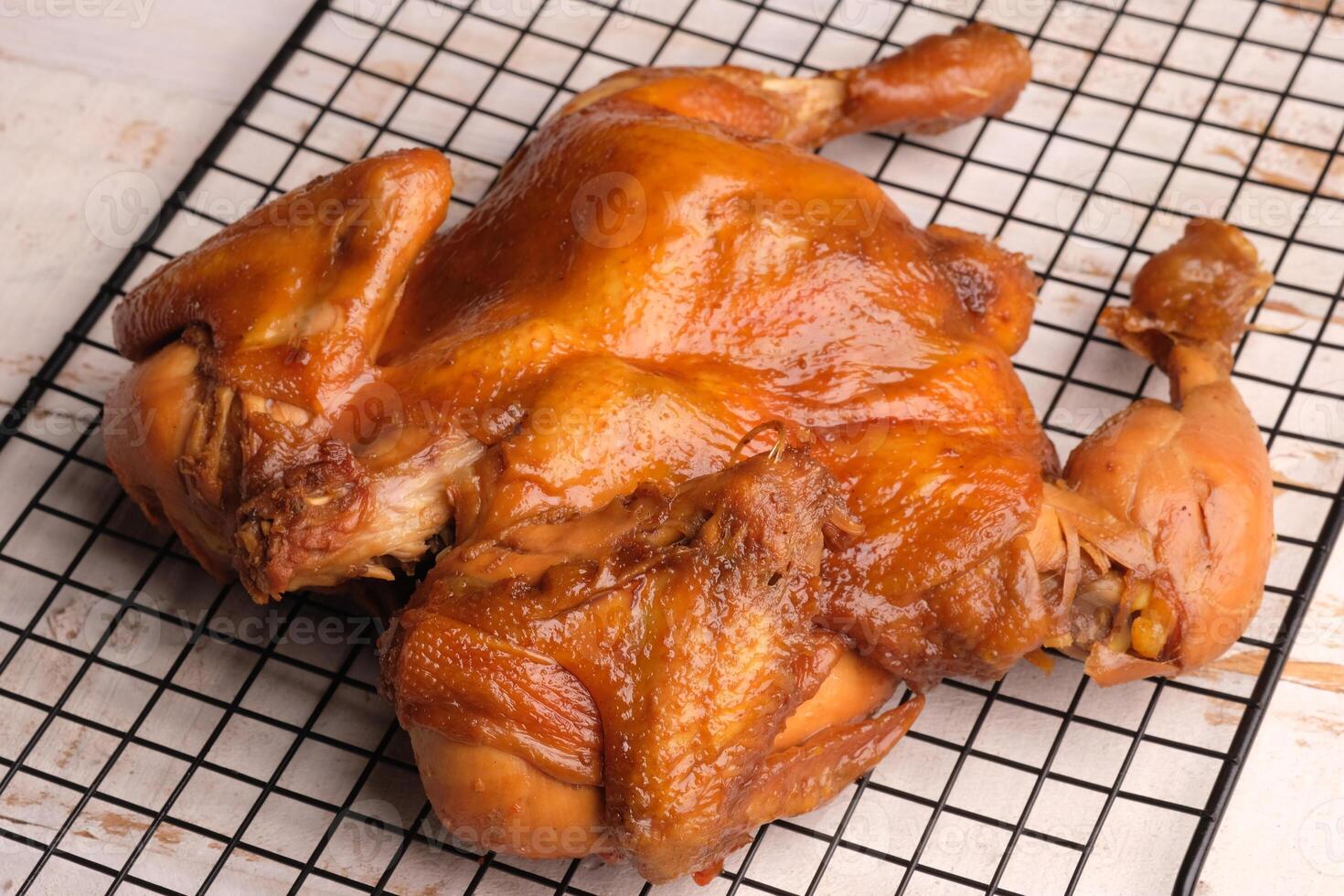 Ayam Panggang. Whole roasted chicken with soy sauce and spices. on the cooling rack. Indonesian food. photo
