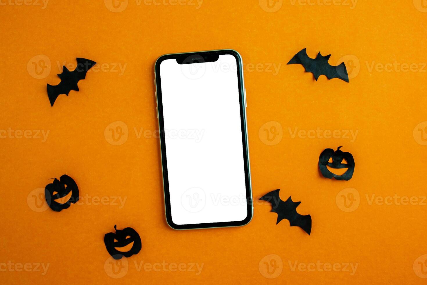 Mockup, smartphone, paper black bats and pumpkins on orange background. Halloween background. photo