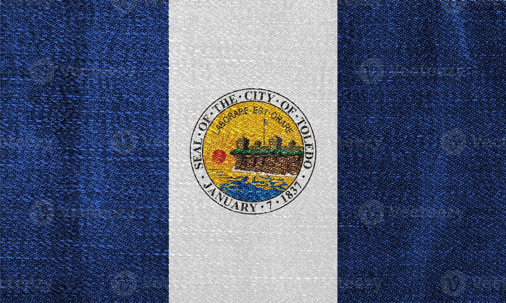 Flag of the city of Toledo, Ohio, USA, on a background of fabric texture. Conceptual collage photo