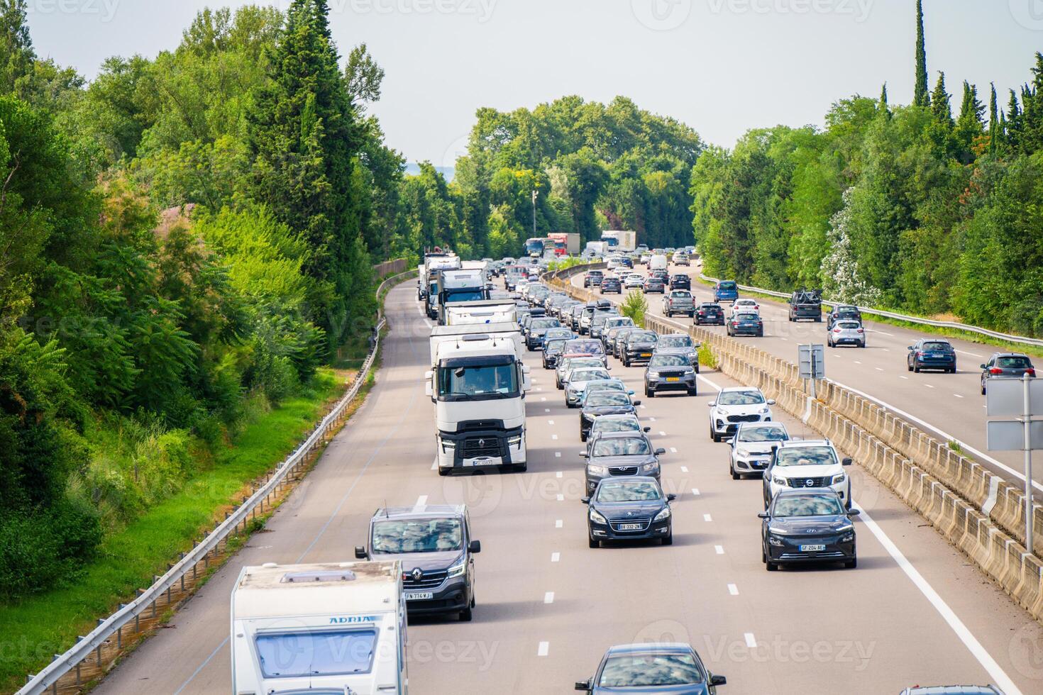 The highway is experiencing heavy traffic, set against a backdrop of lush greenery photo