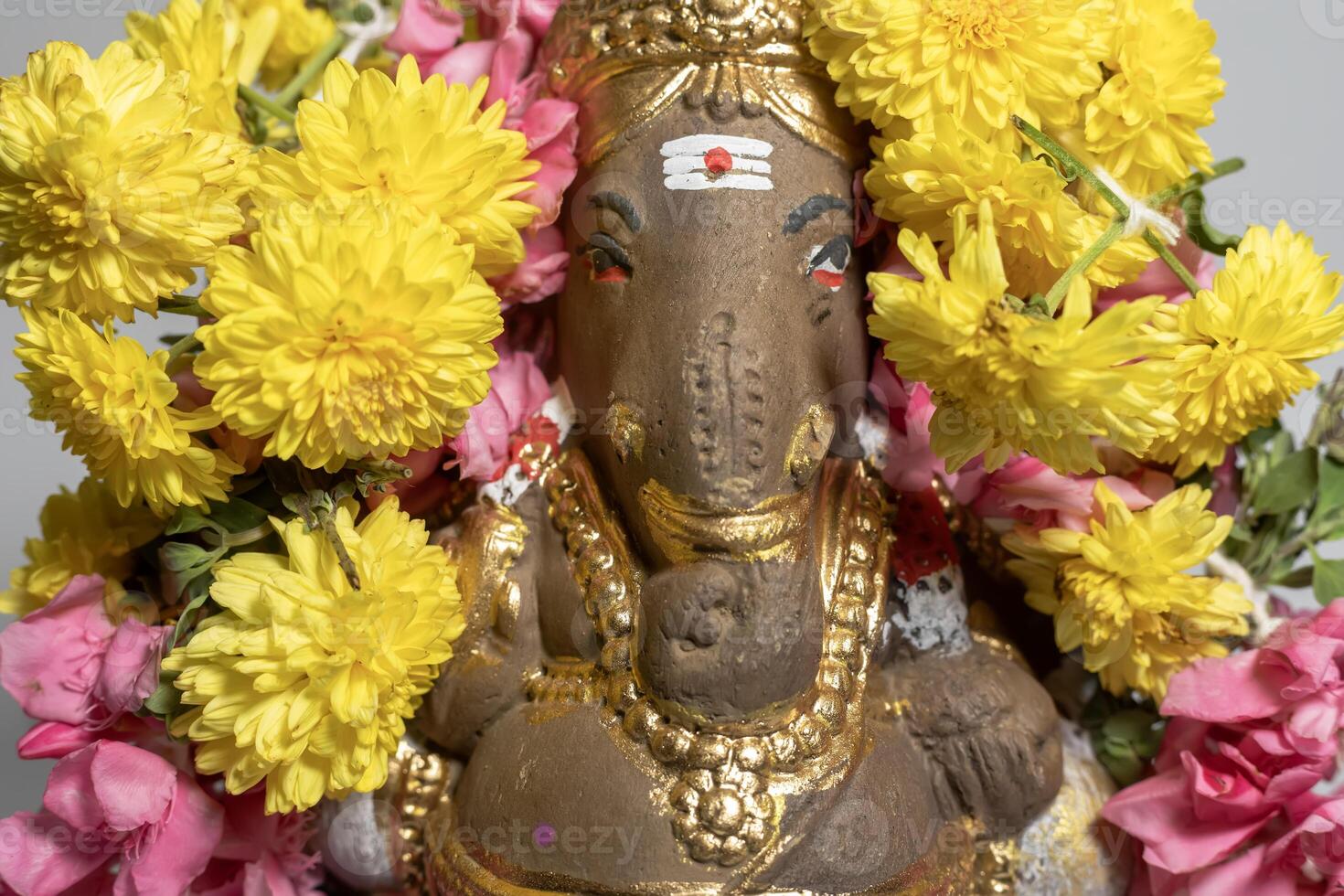 Hindu god Ganesha statue made of clay decorated with flower garlands. photo