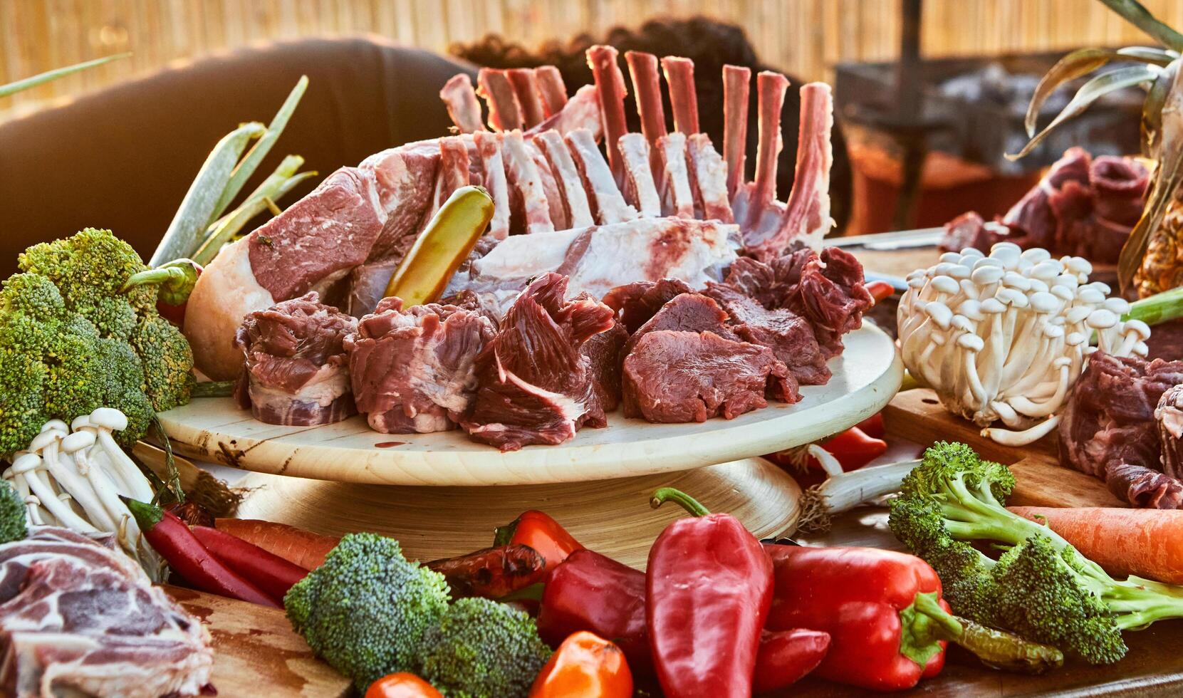 A variety of butchered lamb chops and fresh vegetables laid out on a table, ready for cooking or grilling, with a focus on natural ingredients photo