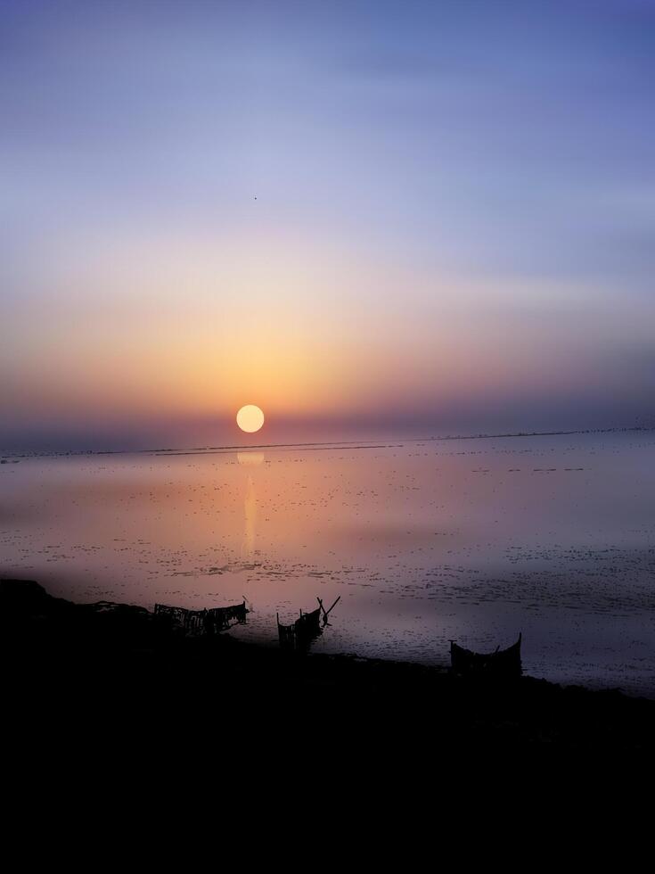 sunset over the evening sky at the beach with boats in the river water, a sunset with a reflection of a sun in the river water. vector