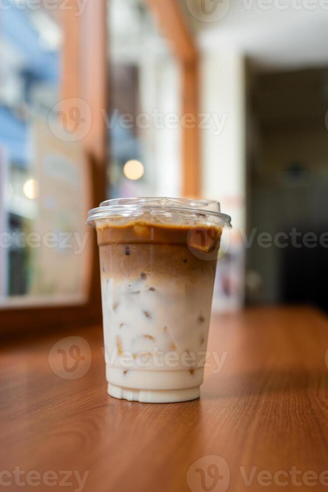 Iced latte coffee with two layers of fresh milk and espresso shot on a wooden table. photo