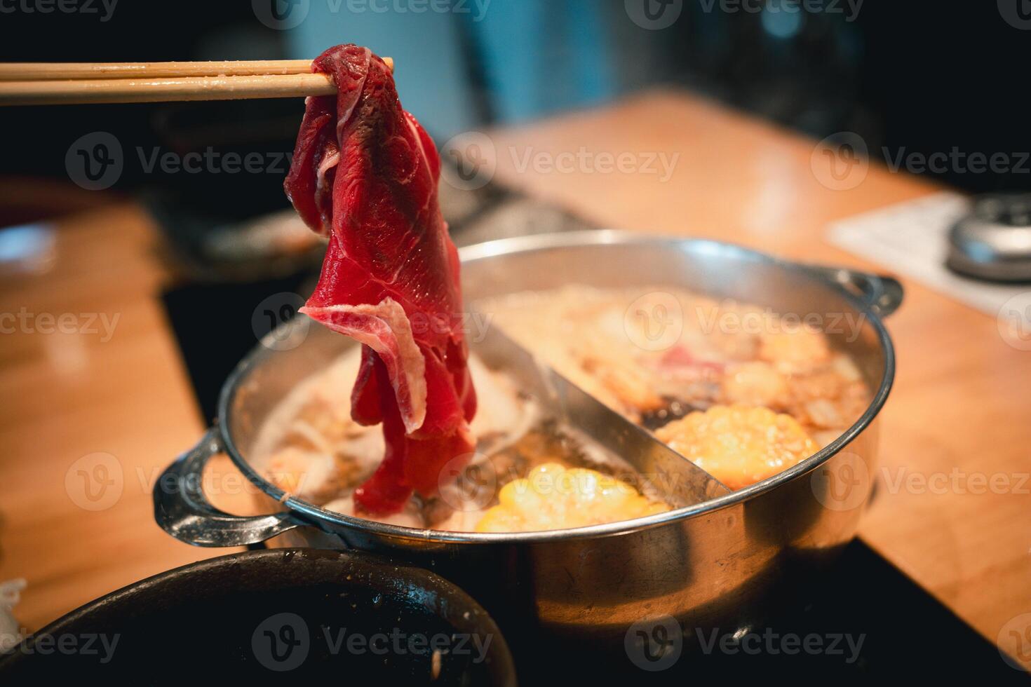 Chopsticks picking up succulent slices of beef to boil in hot pot. photo