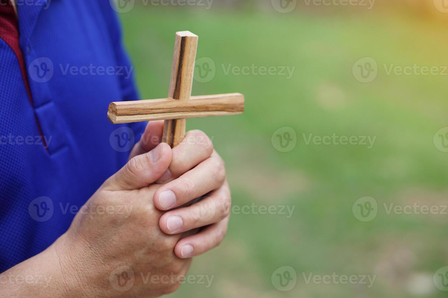 Close up Christian man holding a wooden crucifix to pray. Concept, Christian worship. Faith, forgiveness, belief, love, hope, peace and happiness. Crucifix, religious symbol of Christianity. photo