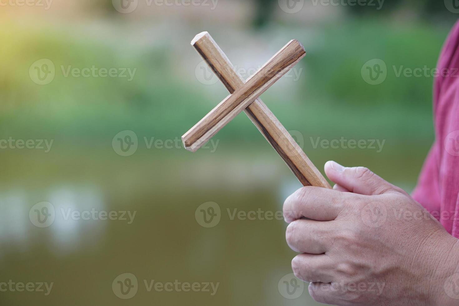 Close up Christian man holding a wooden crucifix to pray. Concept, Christian worship. Faith, forgiveness, belief, love, hope, peace and happiness. Crucifix, religious symbol of Christianity. photo