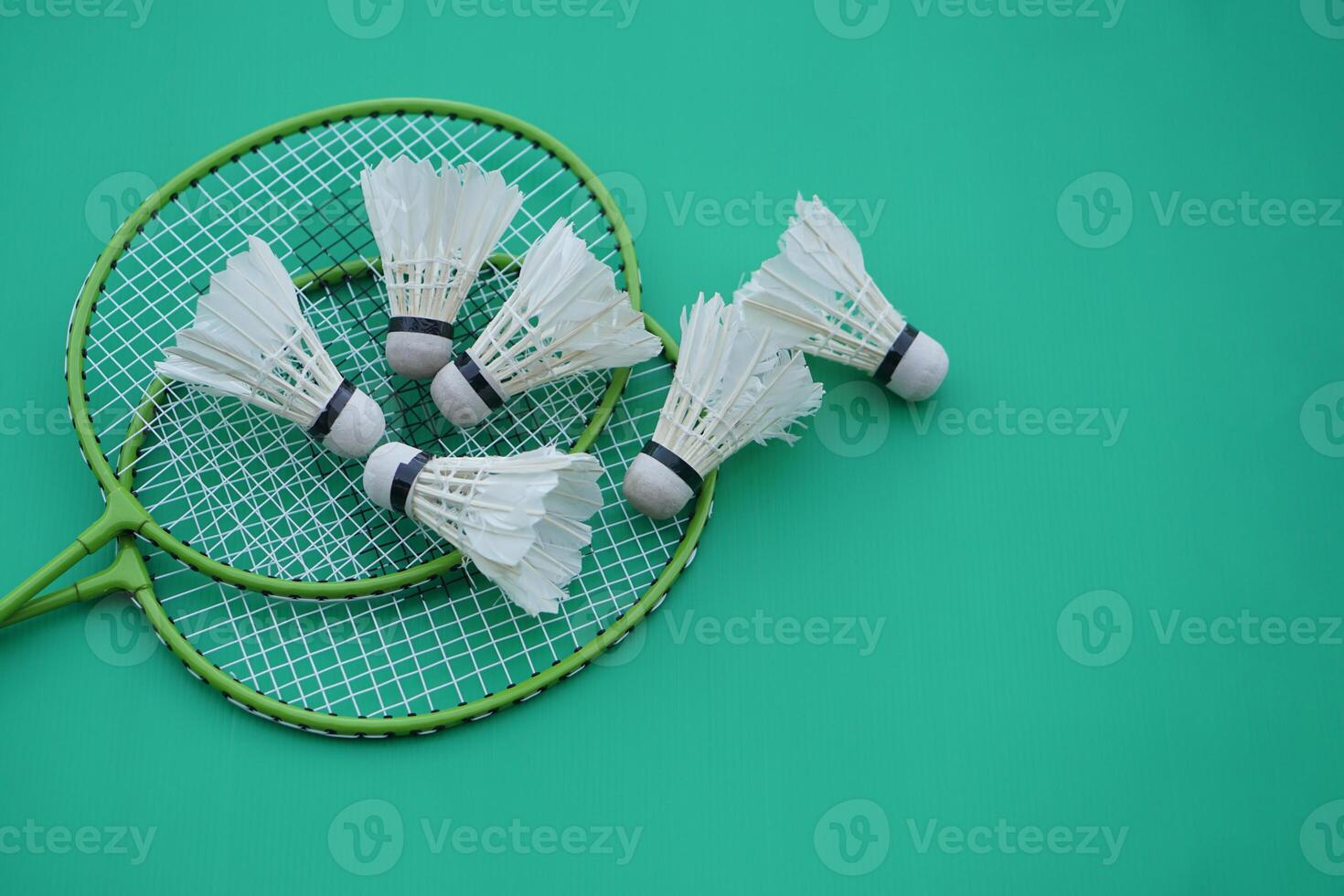 Shuttlecock and rackets. Badminton sport equipments on green background. Concept, sport, exercise, recreation activity for good health. Popular sport for all genders photo