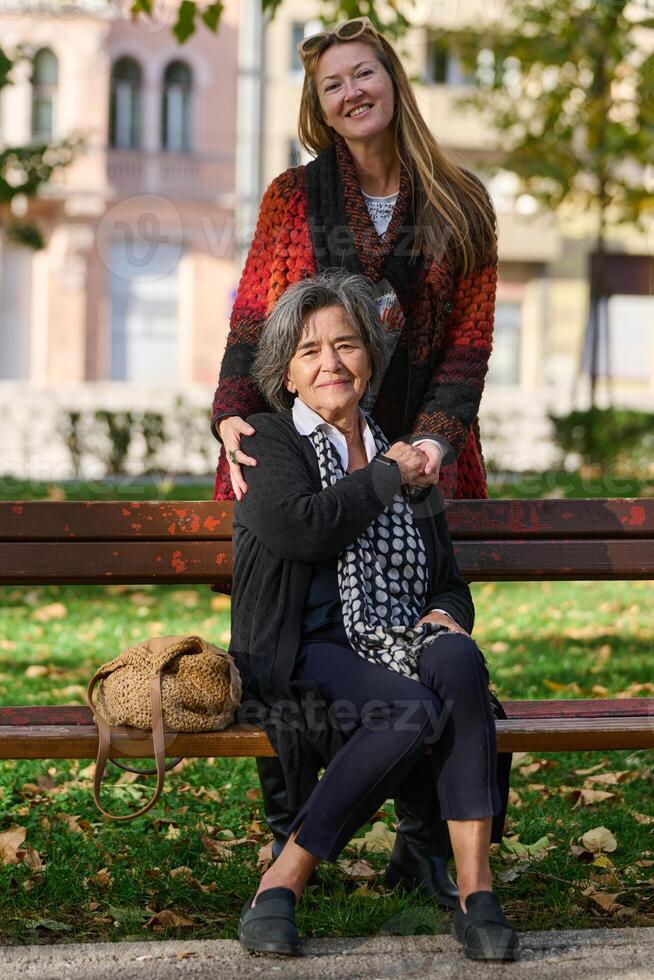 Embracing Generations. A Daughter's Love and Support for Her Senior Mother on a Sunny Day in the Park photo