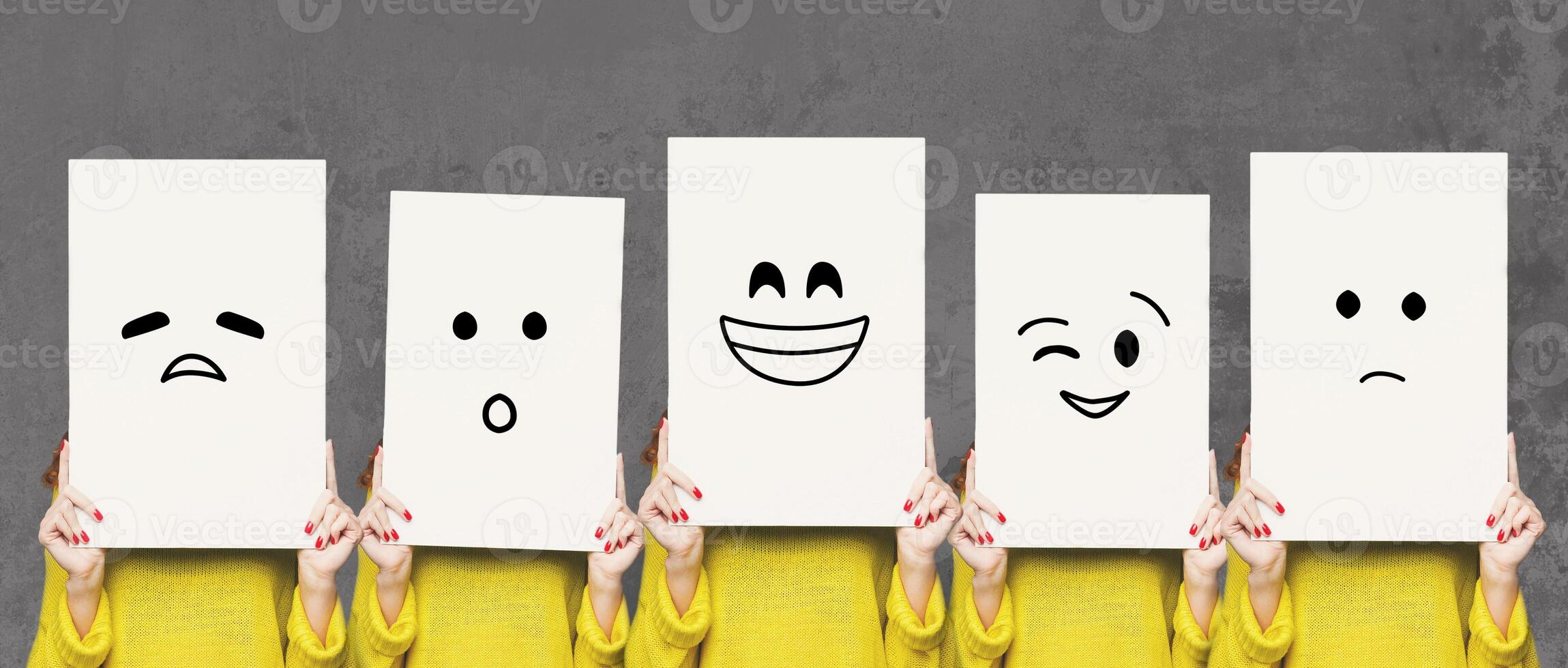 Emotions set. Girl hiding face behind signboard with drawn smileys. Collage of indifferent, winking, happy, surprised, and sad emoticons. photo