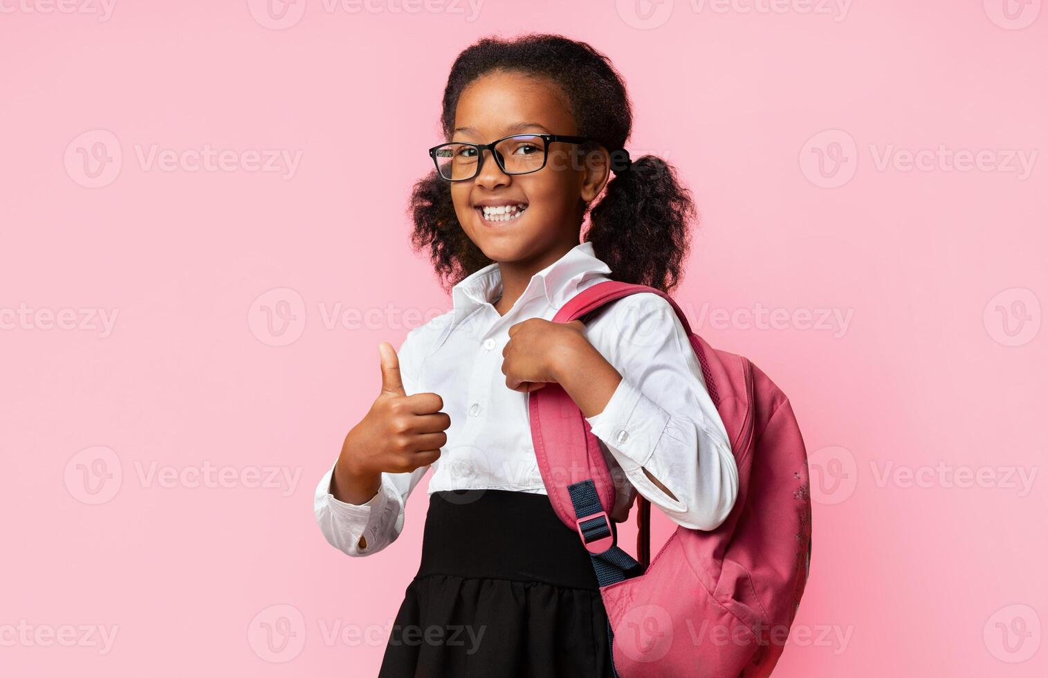 African American School Girl Gesturing Thumbs Up Posing With Backpack And Smiling Over Yellow Studio Background. I Like School photo