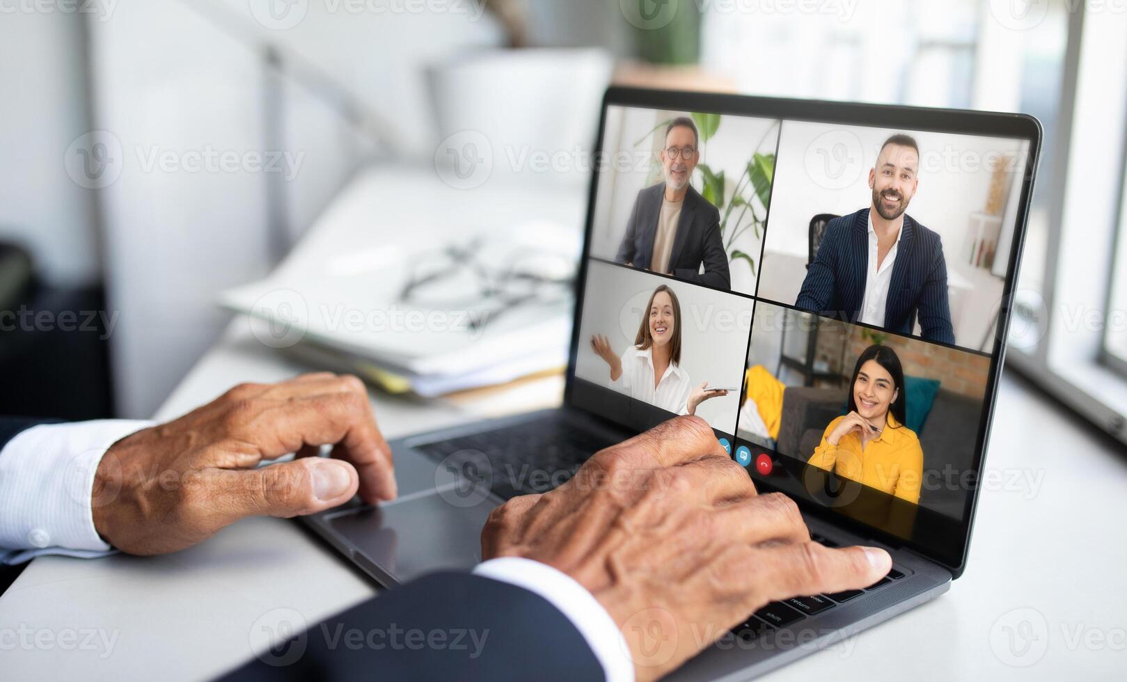 Four professionals are engaged in a virtual meeting using a laptop, discussing business strategies and plans. Participants appear focused and cooperative, ensuring effective communication photo