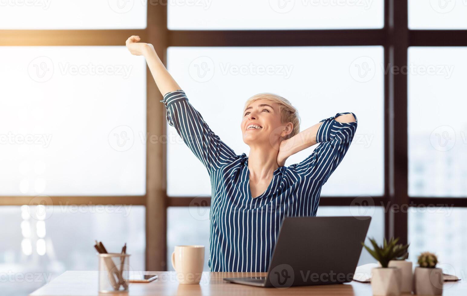 Happy Business Lady At Laptop Stretching Arms Relaxing Pleased With Productive Day At Work Sitting At Workplace Indoor. Selective Focus photo