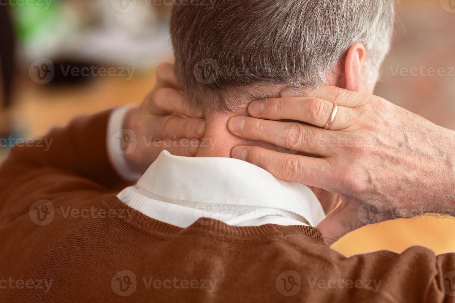 Unrecognizable Elderly Man Having Neck Pain Suffering From Arthritis Massaging Aching Nape Sitting On Sofa Indoor. Rear View, Selective Focus photo