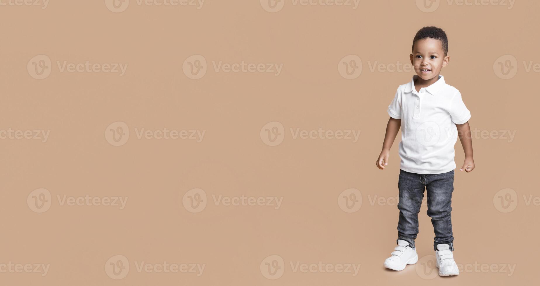 Full length portrait of smiling little black boy in jeans and white t-shirt on yellow studio background photo