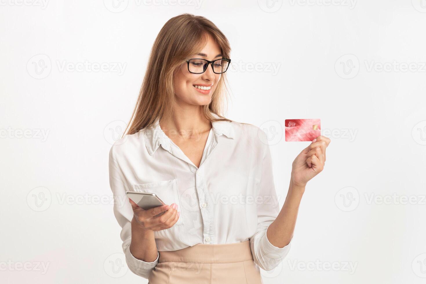 Online Banking. Joyful Businesswoman Using Phone And Credit Card Standing In Studio Over White Background photo