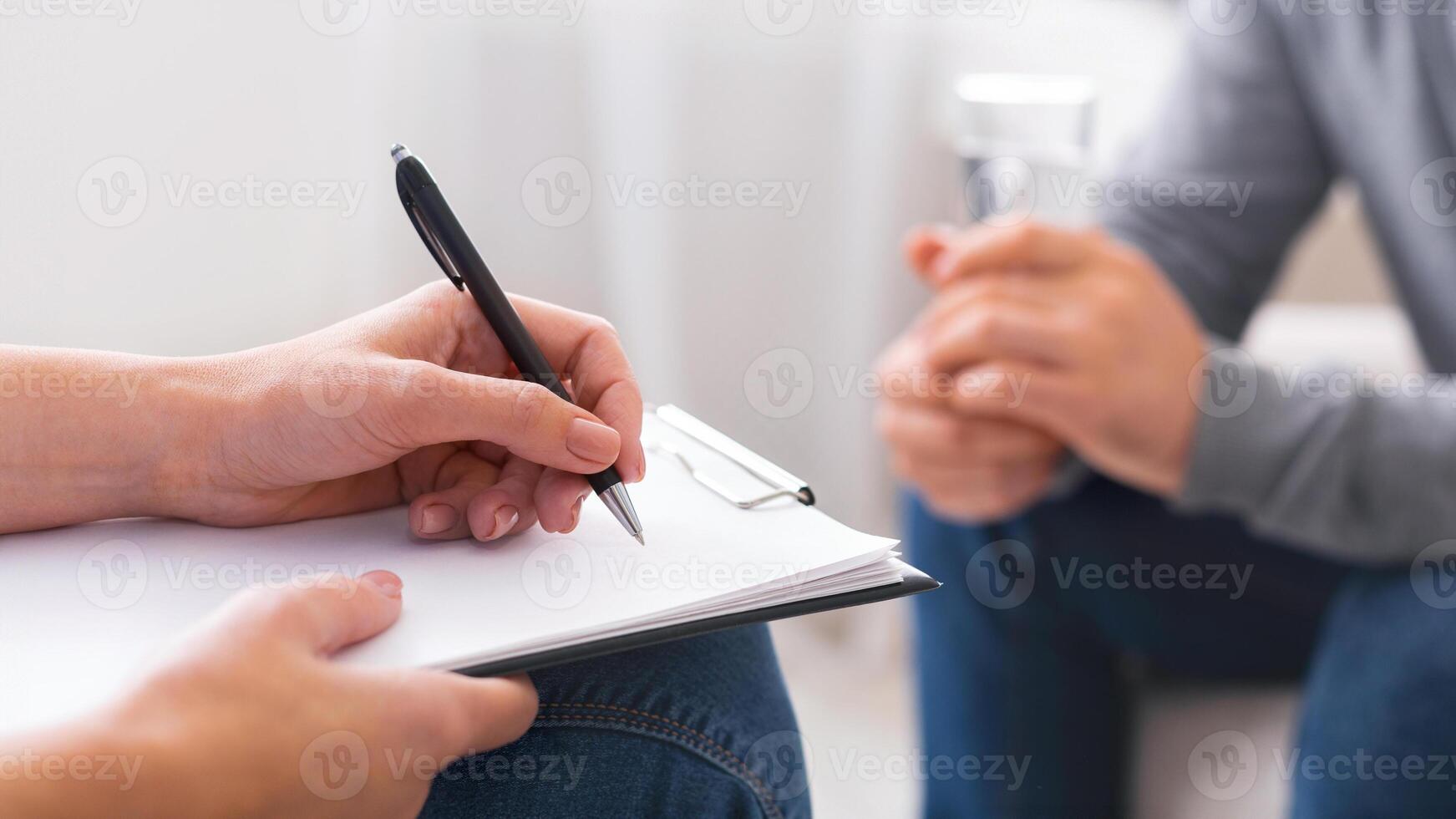 Psychologist taking notes during session with depressed patient, close up, panorama photo