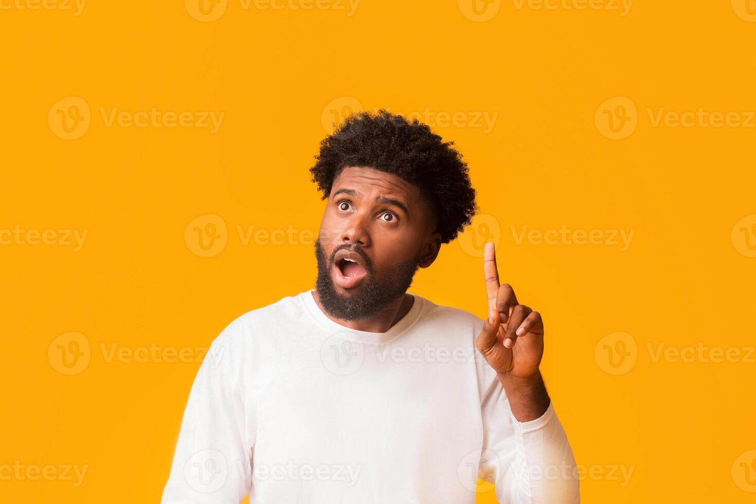 Young african american shocked man having idea, pointing finger up, got problem solution, orange studio background, empty space photo