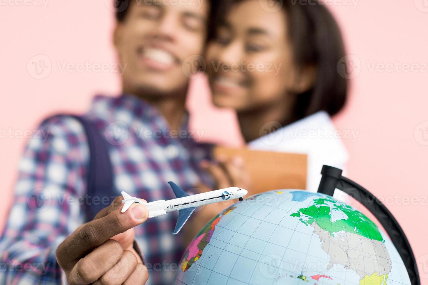 African American couple is holding a model airplane and a globe in their hands, showcasing a shared passion for travel and exploration. The model airplane symbolizes a desire for adventure photo