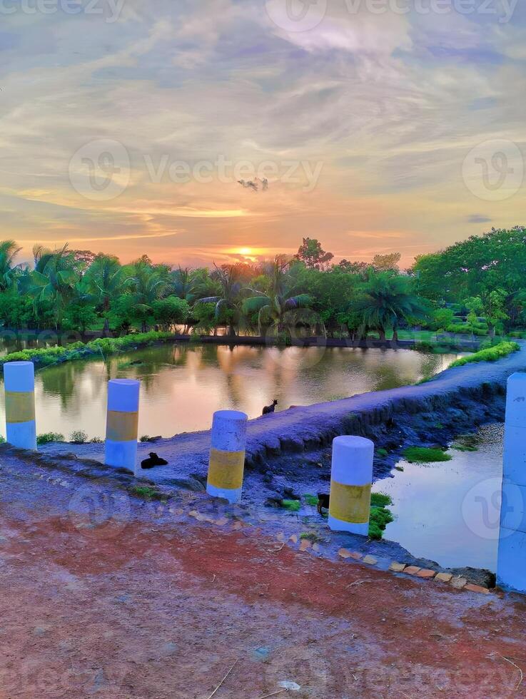 painting of a lake with the sun setting behind it photo