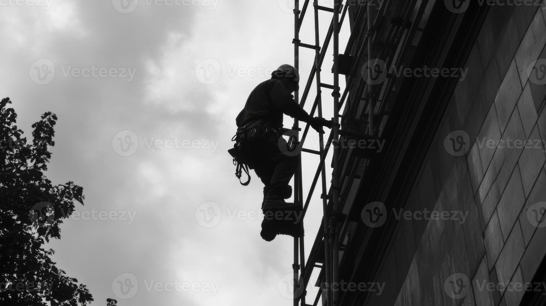 Silhouetted Worker on Scaffolding Against a Cloudy Sky photo