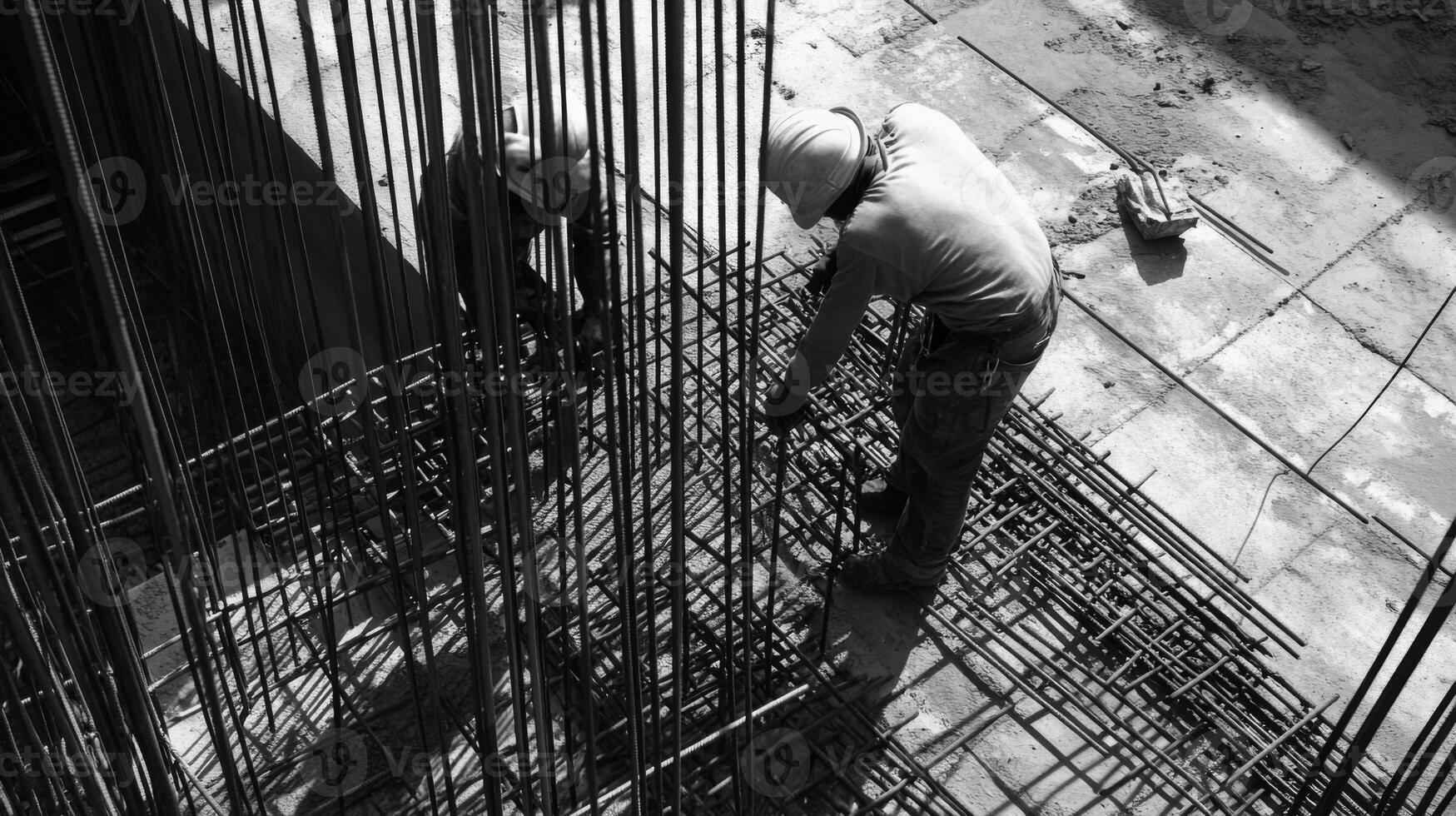 Construction worker securing rebar in concrete foundation photo