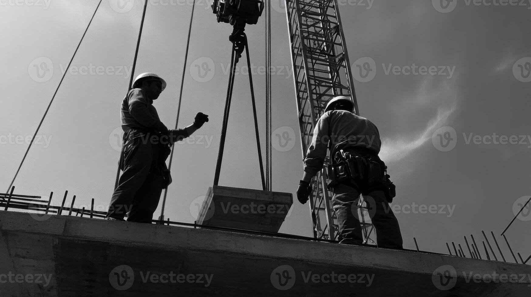 Two Construction Workers on a Partially Built Concrete Structure with a Crane photo