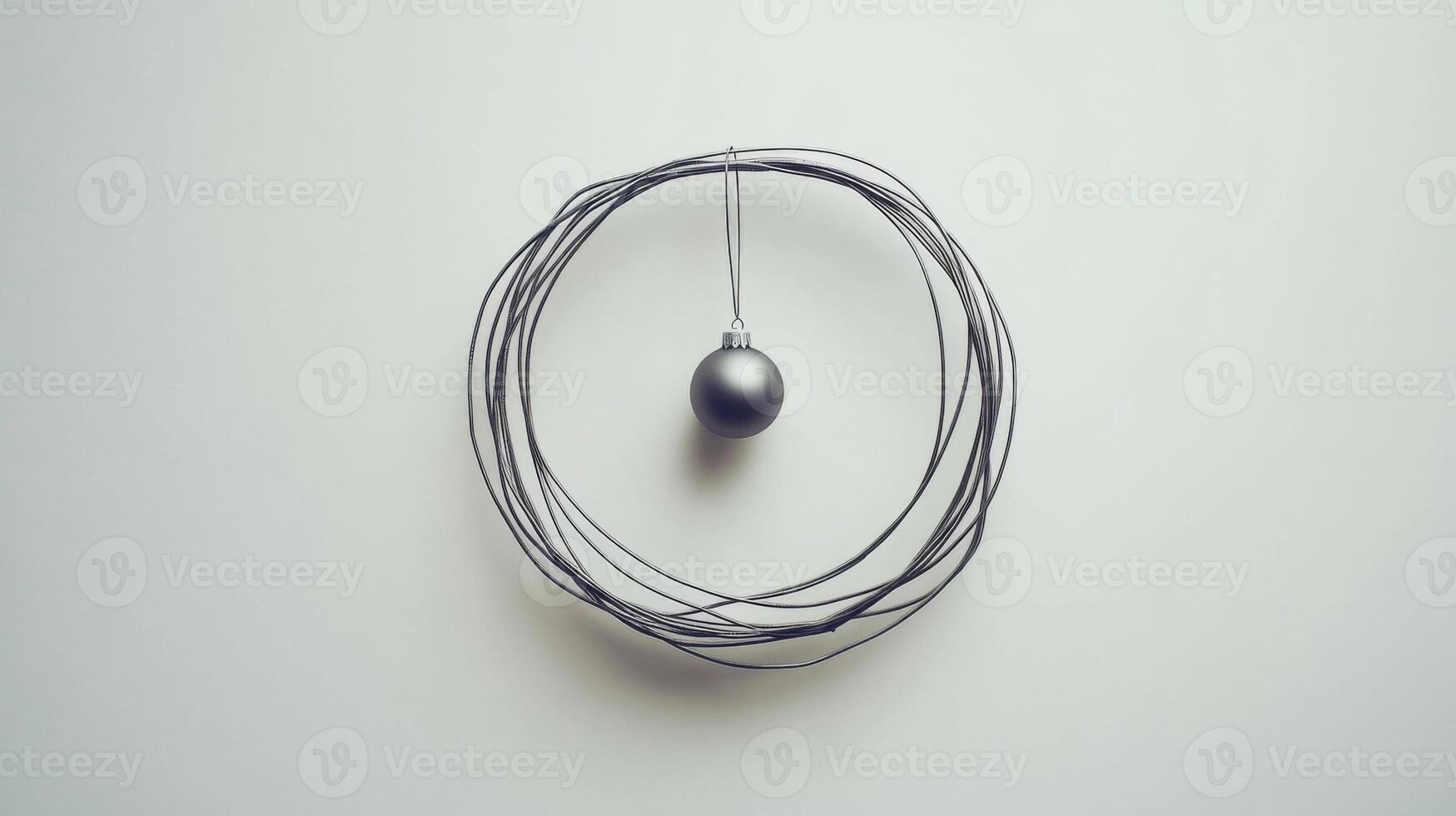 A single silver Christmas ornament hanging from a wire wreath against a white background photo