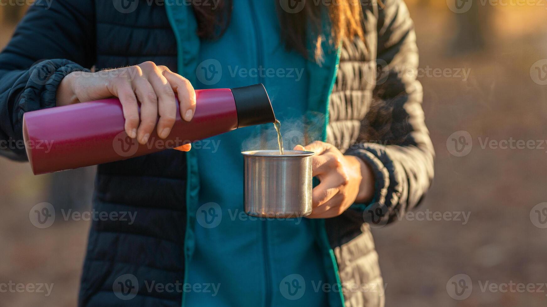 Close up of woman hands pouring tea into camping mug photo