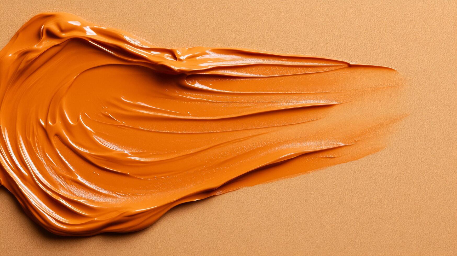 Creamy texture of spiced orange foundation swatch softly melting into an almond colored background photo