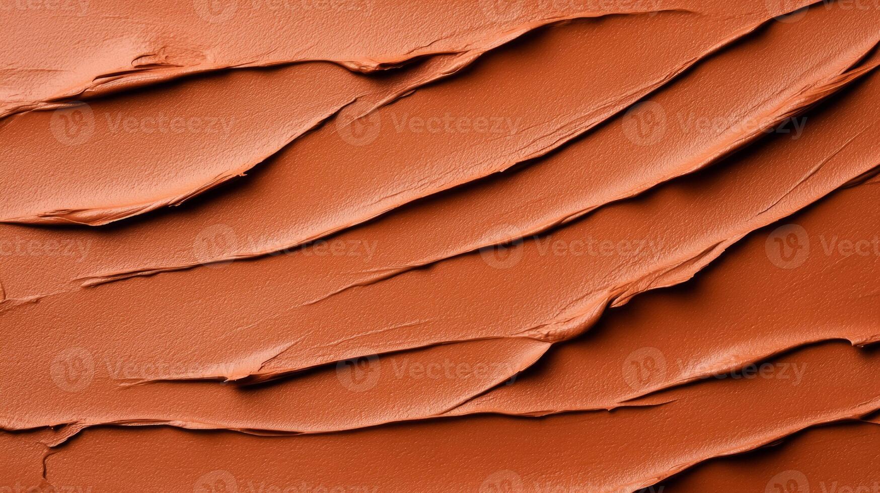 Closeup of terracotta clay mask smeared in rough organic lines on a smooth beige background photo