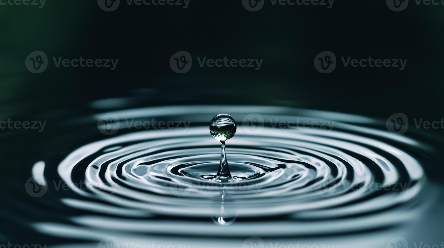 Extreme close up of a single raindrop landing on a reflective surface causing ripples photo