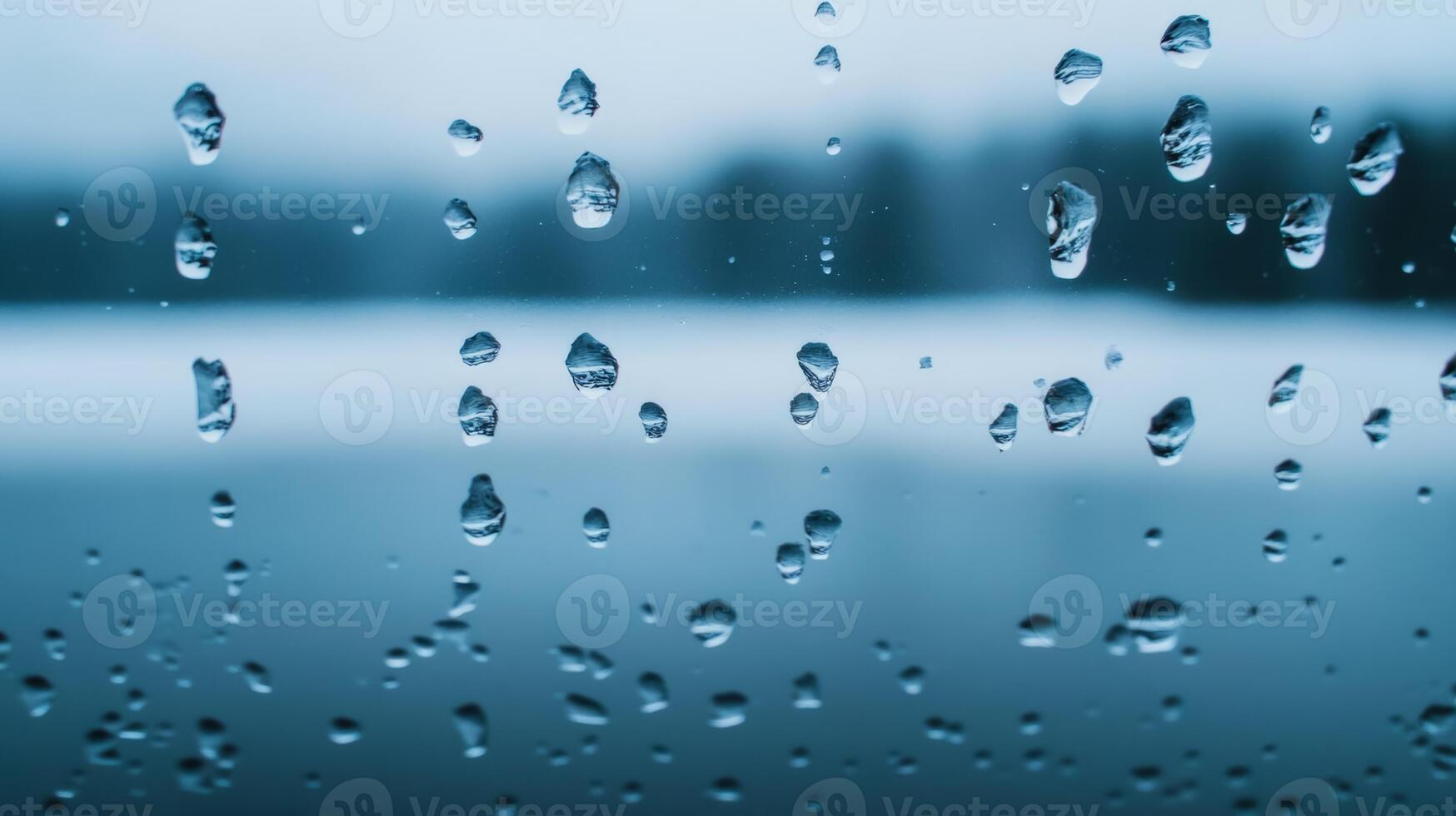 Cold rain droplets on a glass window against a frosty winter landscape background photo