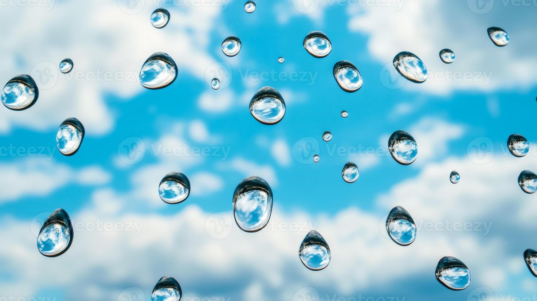Drops of water on a glass surface reflecting a blue sky with fluffy clouds photo