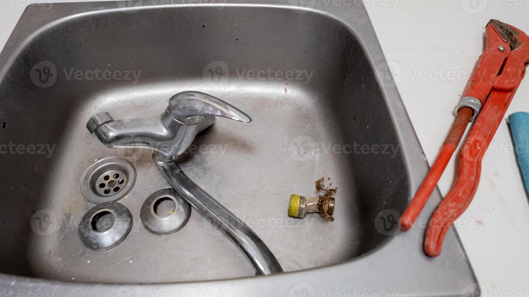 A sink undergoing repair with a disassembled faucet and tools, highlighting home maintenance and plumbing issues photo
