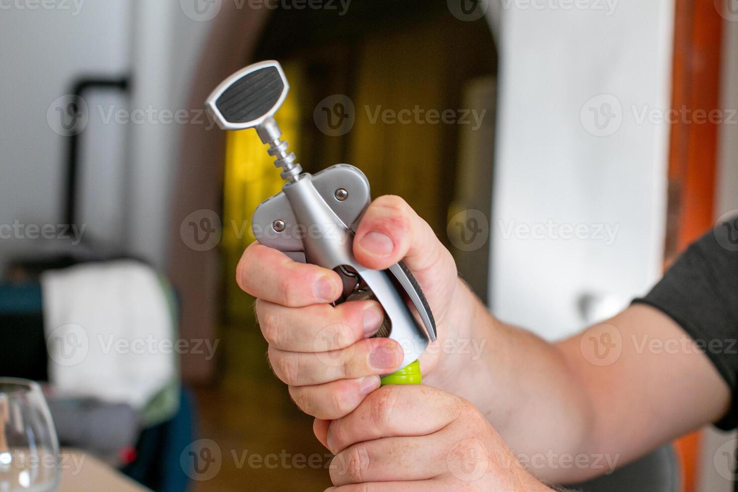 A person opening a wine bottle using a corkscrew, symbolizing celebration and relaxation at home photo