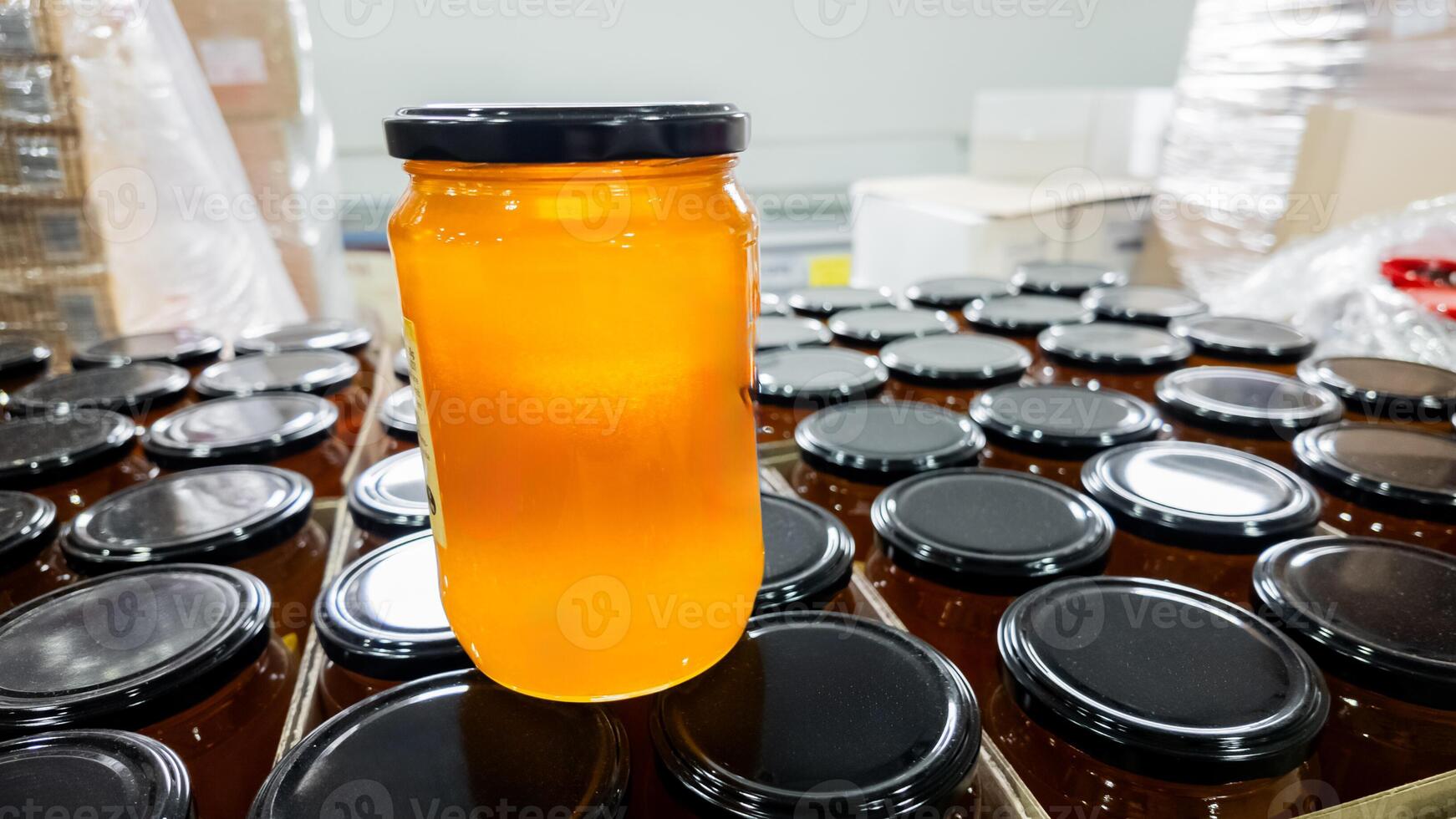 A jar of golden honey on top of other jars in a factory, symbolizing Thanksgiving preparations and organic food production photo