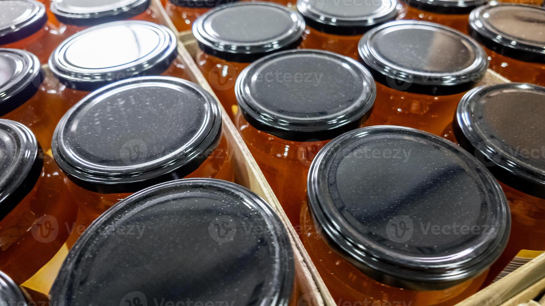 Close up of neat rows of honey jars with black lids, perfect for concepts of natural food and Christmas gifts photo