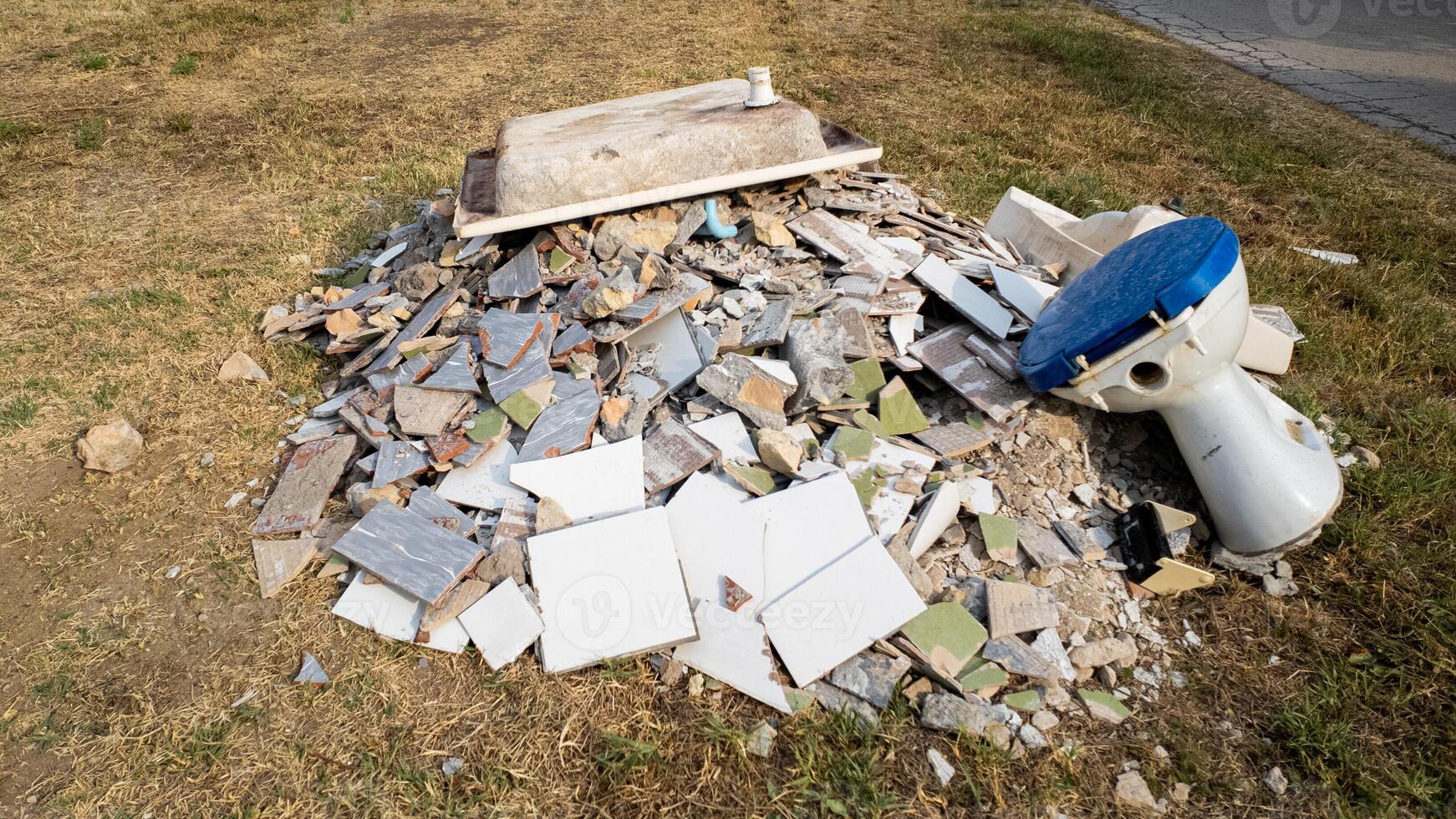 A pile of construction debris and an old toilet discarded improperly, highlighting the issue of illegal dumping and waste management problems photo
