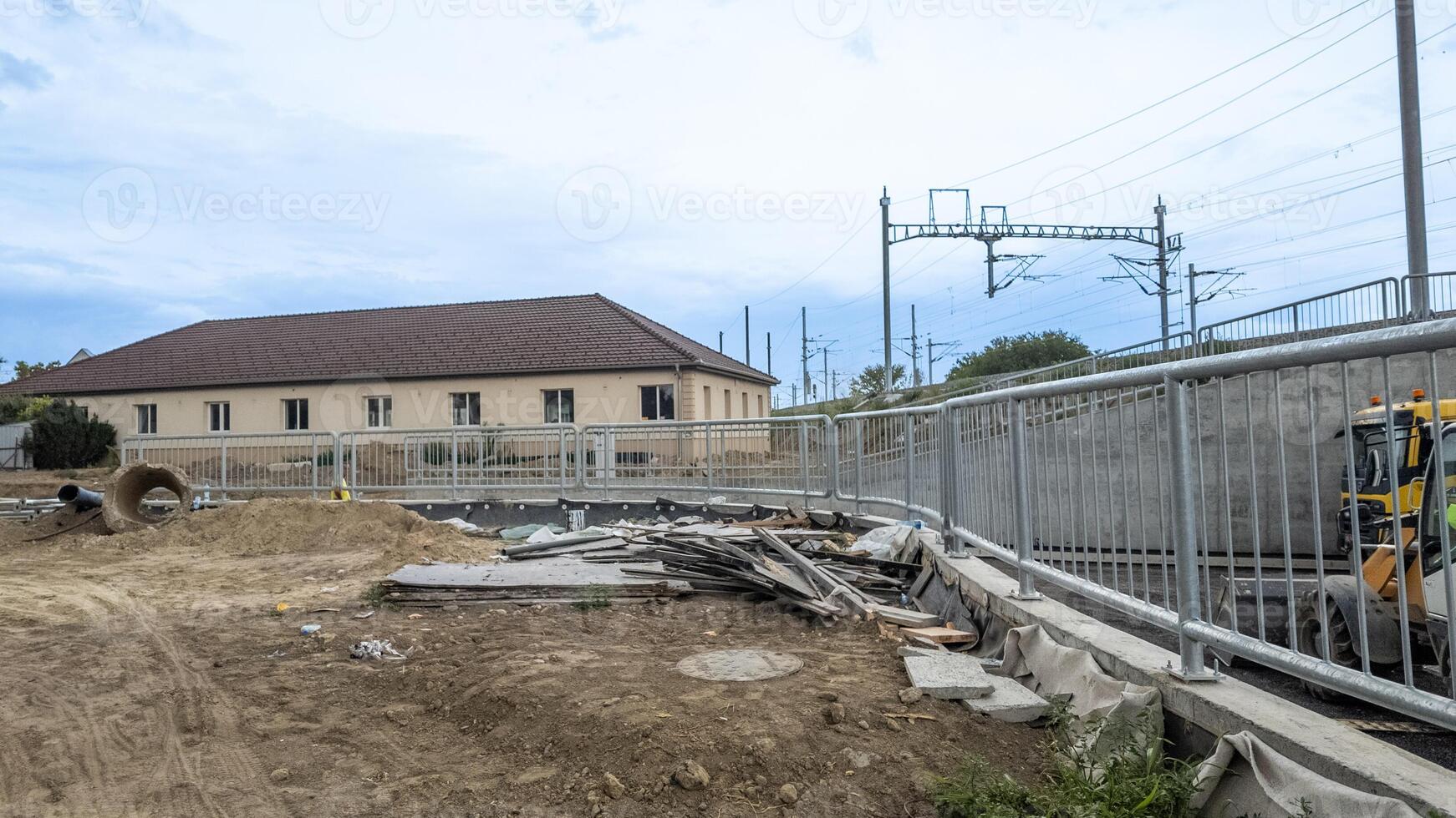 Construction site near railway tracks with scattered materials and fenced off area, showing urban development progress issues photo