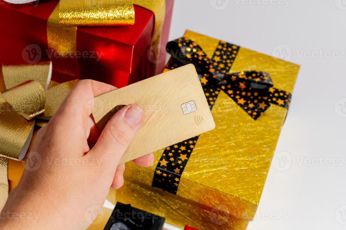 A person holding a credit card over holiday gifts, illustrating the concept of Christmas shopping and festive spending photo
