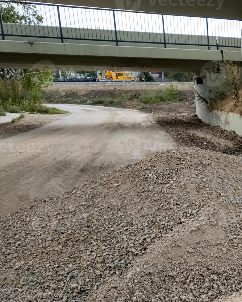Underpass construction zone with gravel piles and machinery representing infrastructure development and roadwork challenges photo