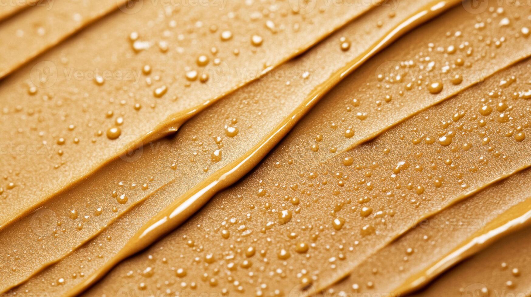 Closeup of golden brown eyebrow gel with tiny microfibers creating a textured pattern against a light tan background photo