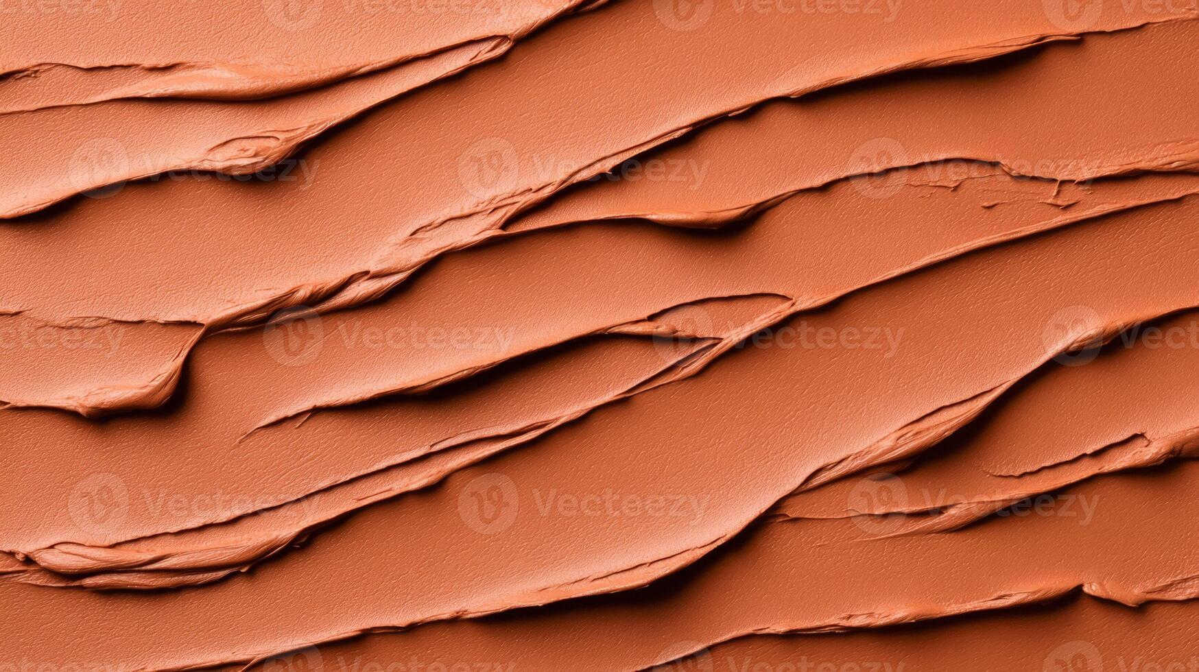 Closeup of terracotta clay mask smeared in rough organic lines on a smooth beige background photo