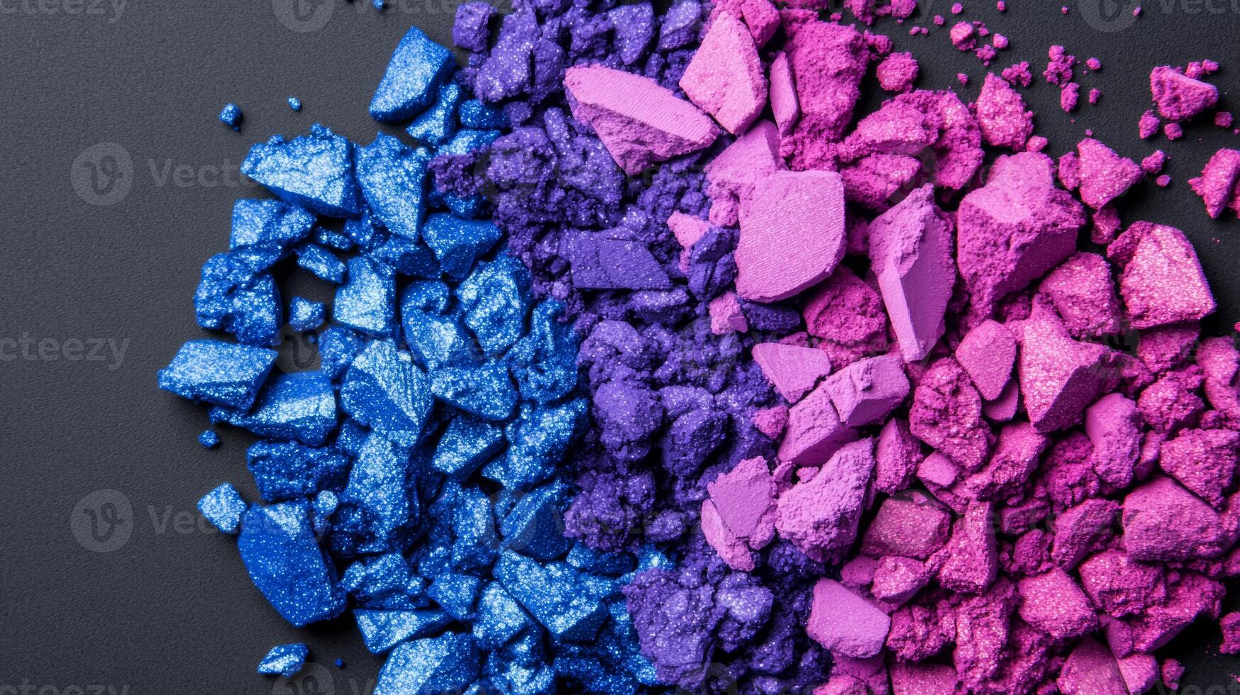 Crushed jewel toned eyeshadow powders in sapphire and amethyst shades creating a colorful textured background photo