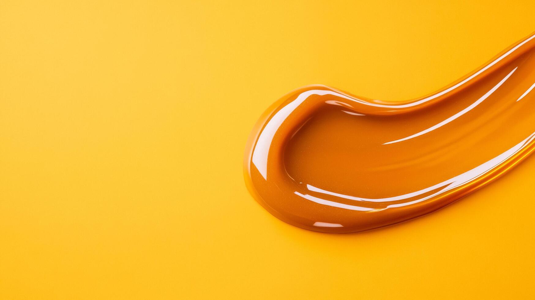 Glossy caramel lip gloss in a thick luminous droplet with highlights catching warm light on a creamy background photo