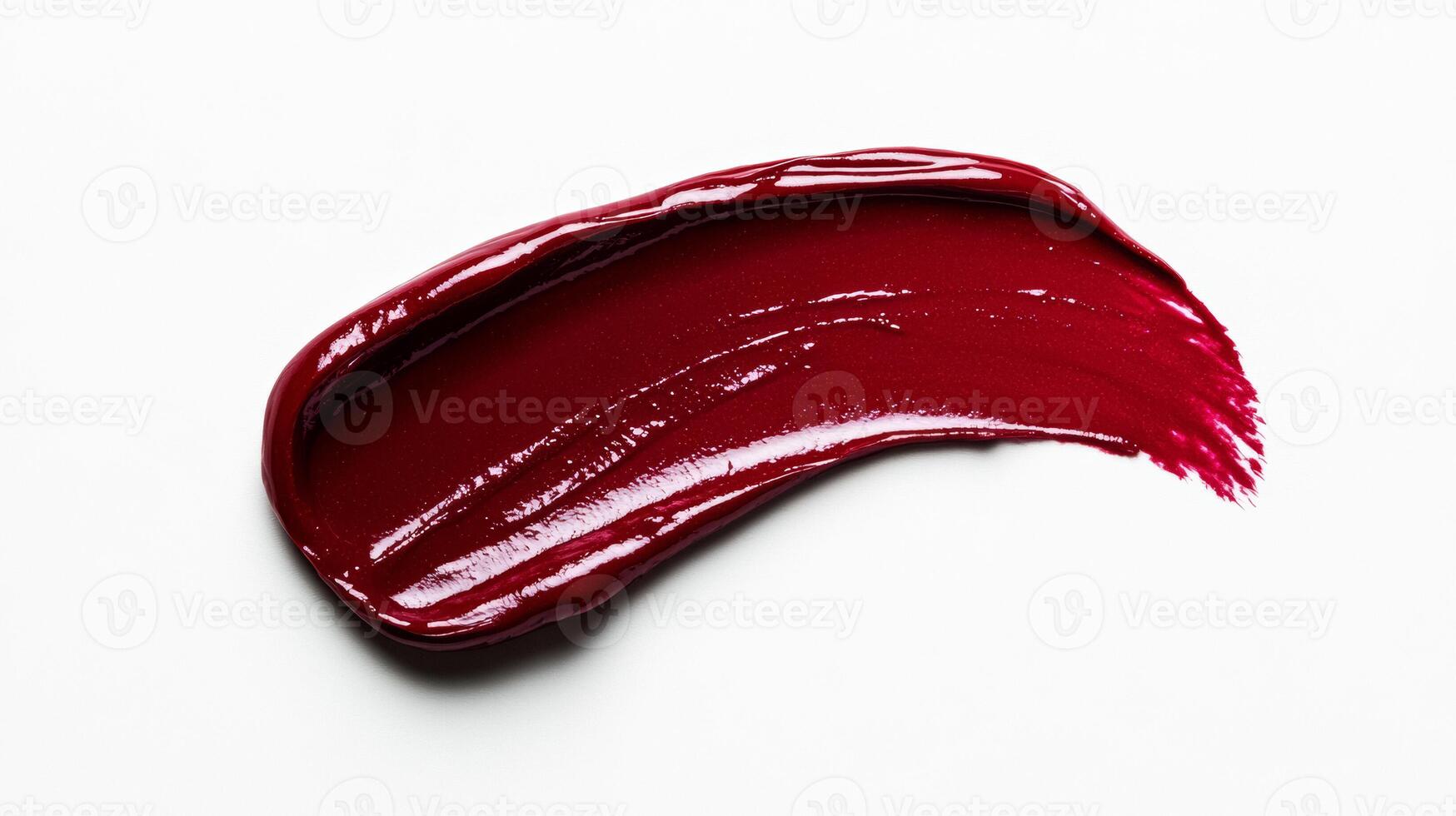 Rich burgundy lipstick smudge with soft feathered edges and glistening highlights on a matte white background photo
